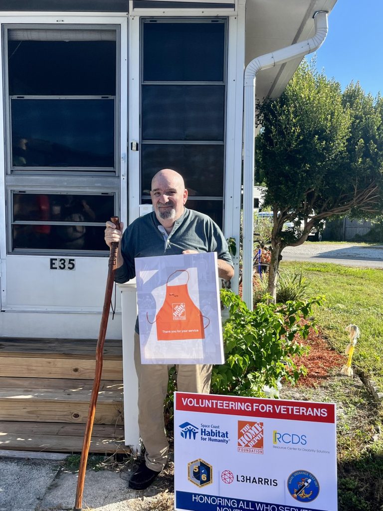 Veteran posing with sign made from Home Depot. 
